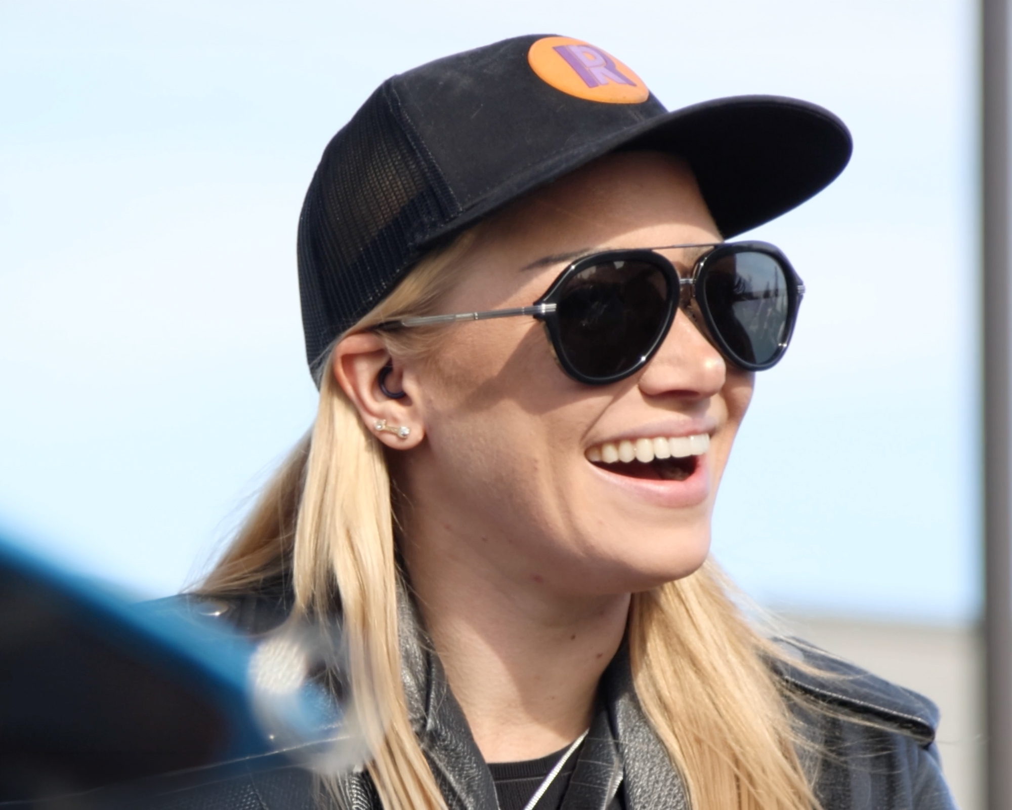 A smiling attendee in a black cap and sunglasses at the show